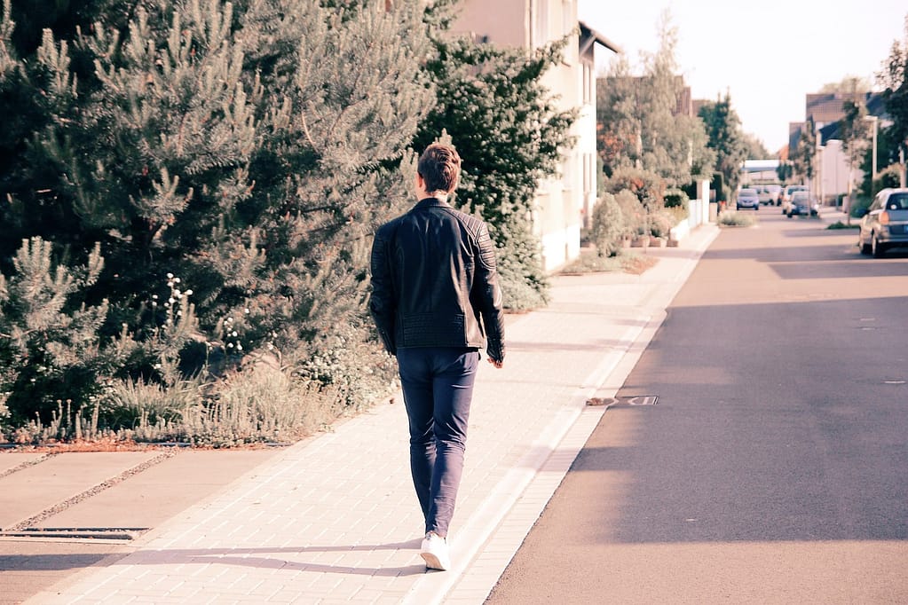 A man walking down a suburban street in Australia, enjoying a sunny day.