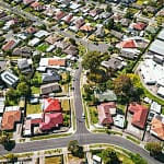 Aerial view of a suburban neighborhood in Melbourne, showcasing rows of houses and green spaces.