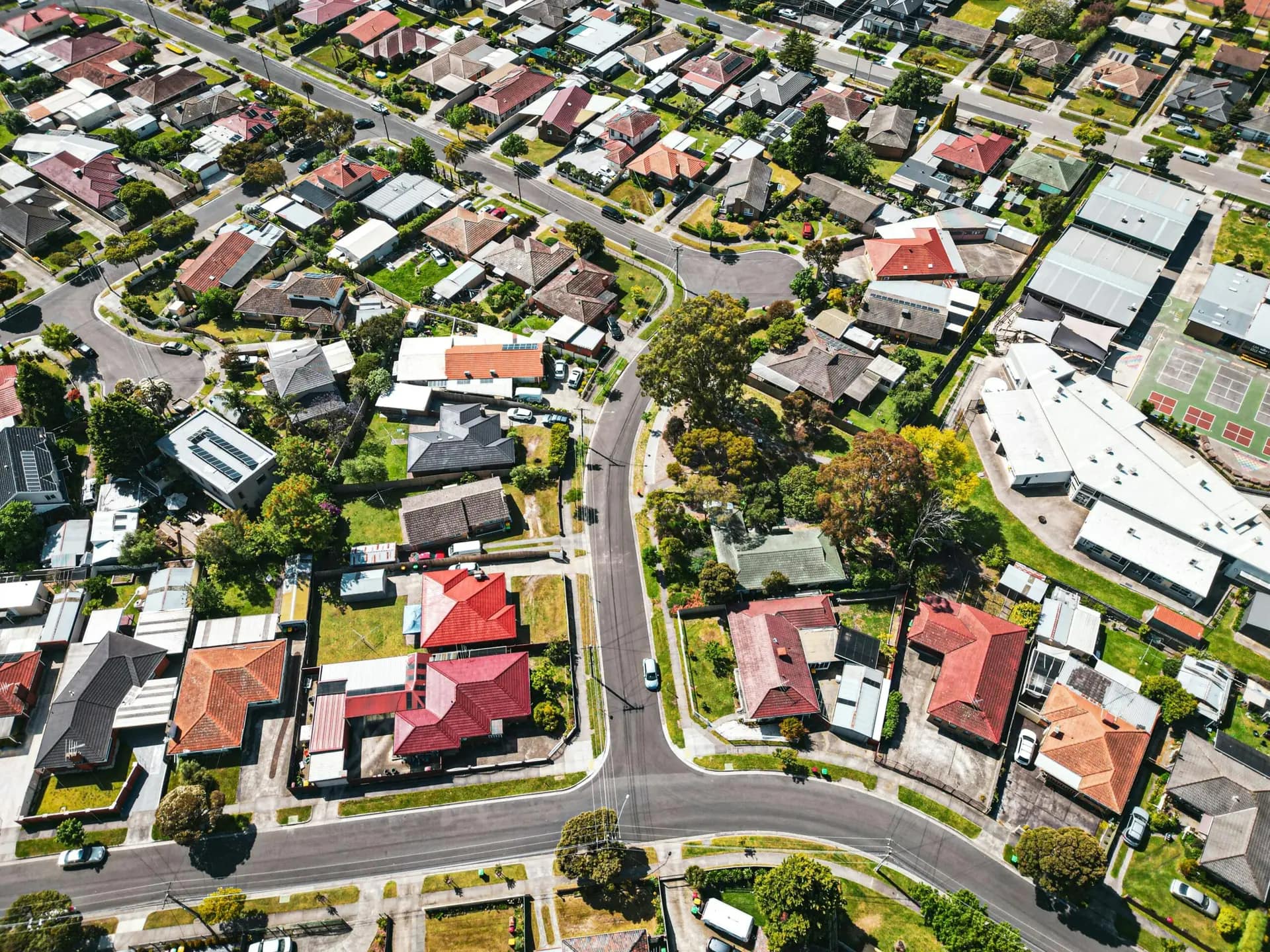 Aerial view of a suburban neighborhood in Melbourne, showcasing rows of houses and green spaces.