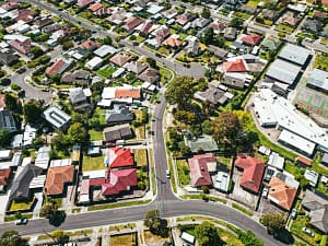 Aerial view of a suburban neighborhood in Melbourne, showcasing rows of houses and green spaces.